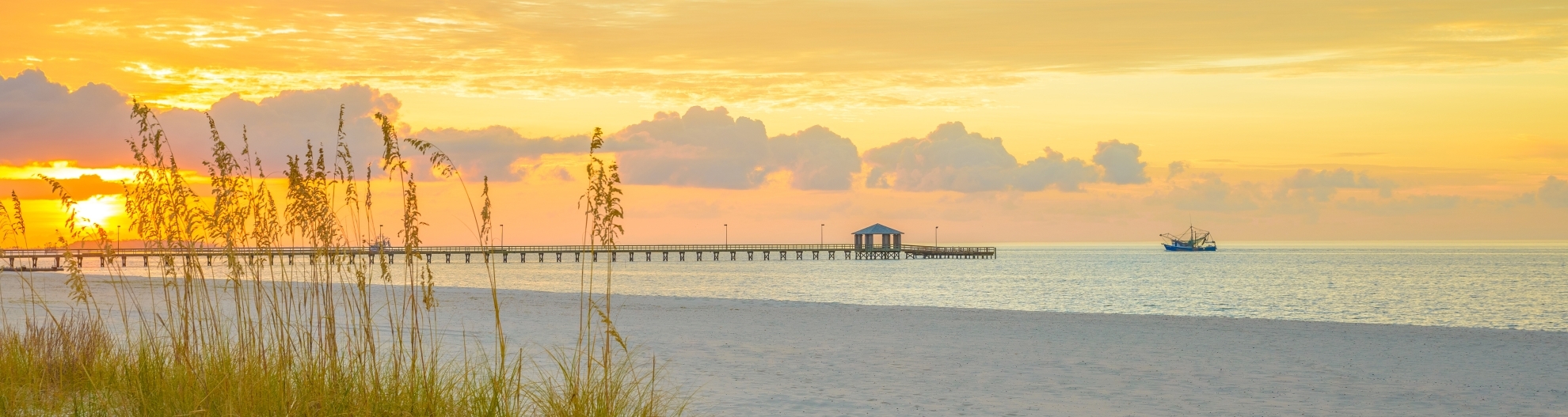 Gulfport Mississippi beach, dramtic golden sunrise, pier, shrimp boat, bay